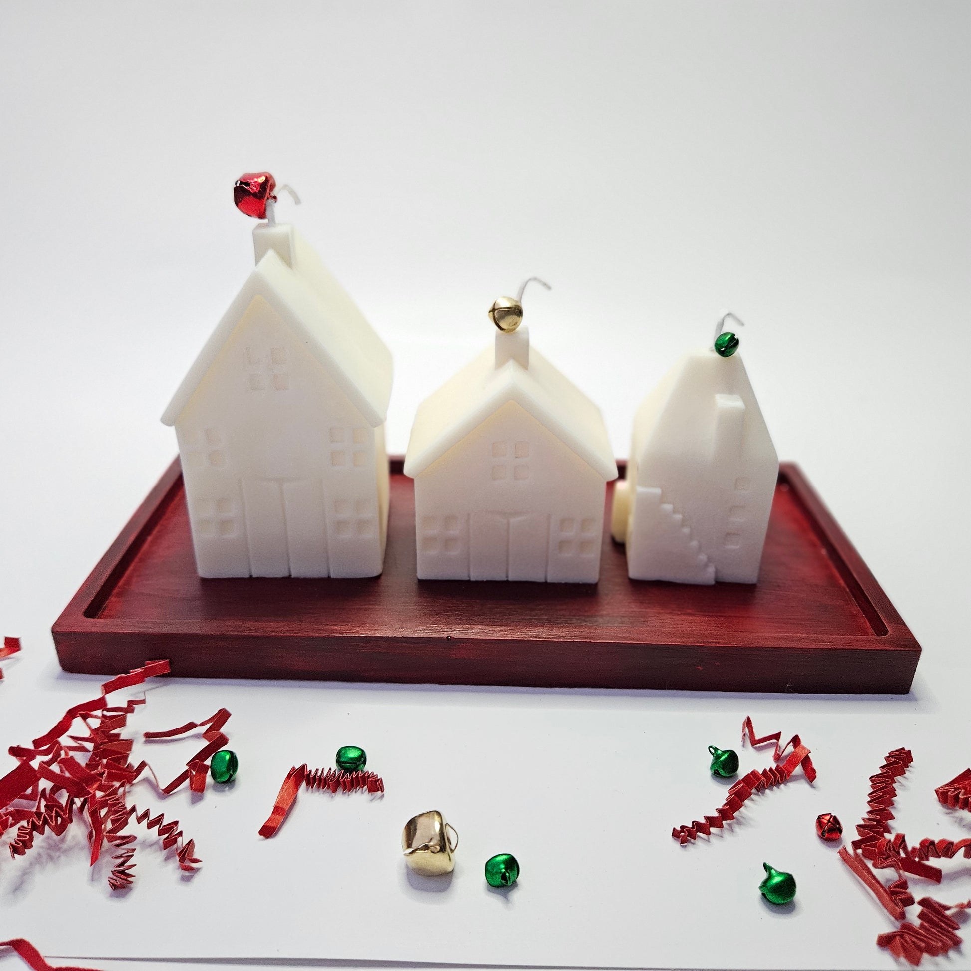 Three white house-shaped candles on a red resin tray