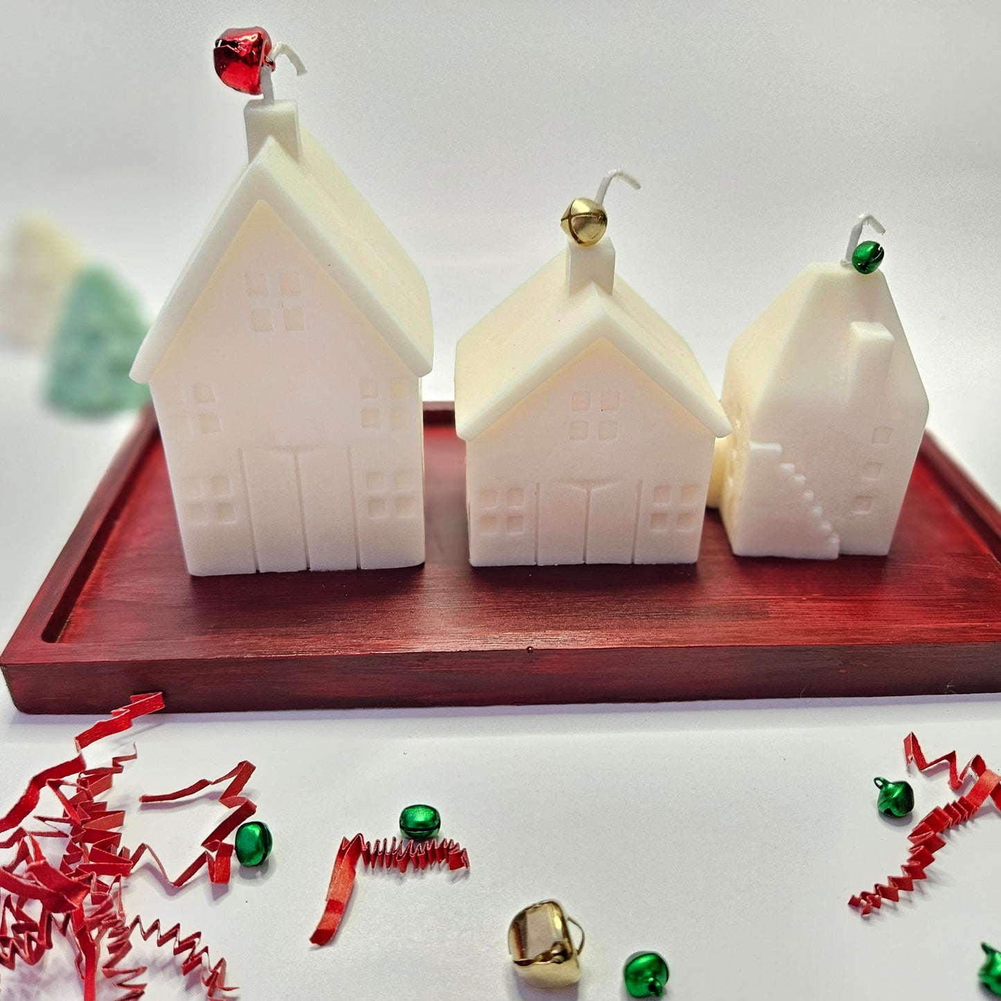 Three white house-shaped candles on a red resin tray