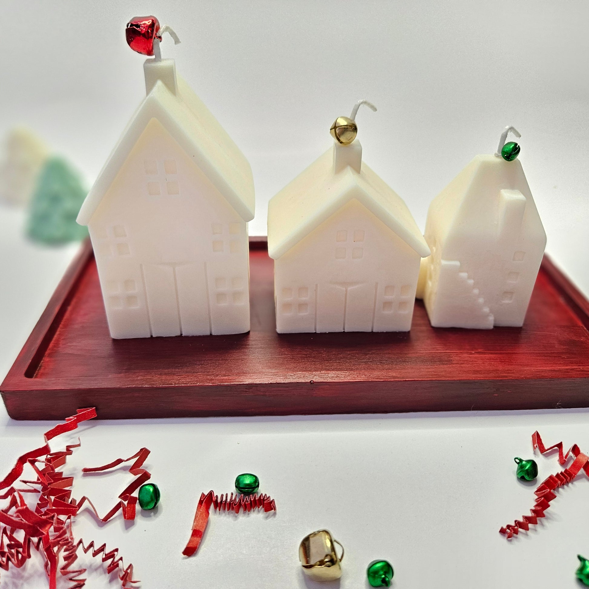 Three white house-shaped candles on a red resin tray